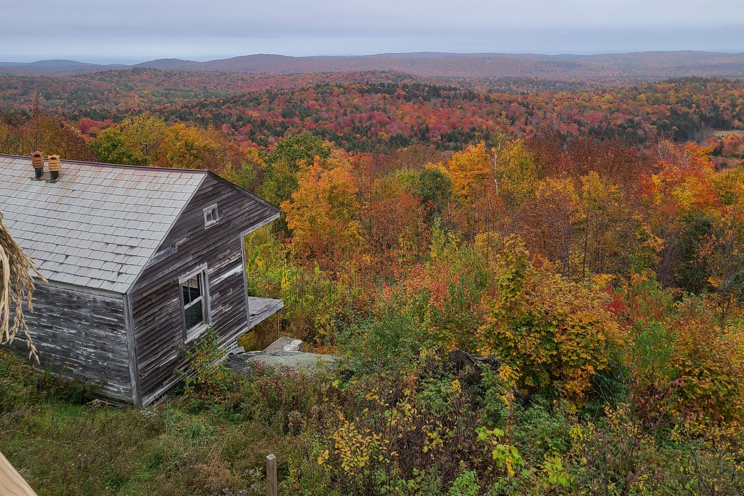 An old house on top of a mountain, with leaves changing all over the landscape